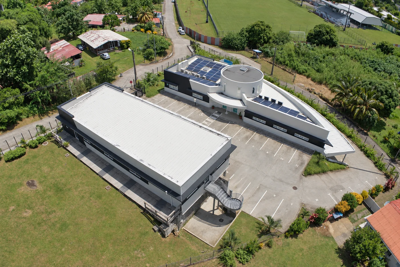 Vue aérienne de bâtiments à Petit-Bourg en Martinique, avec leurs parkings, accès et environnement